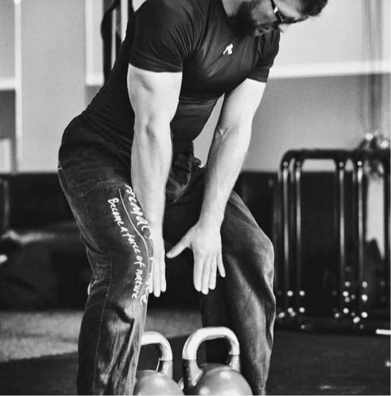Trainer bei einer Übung mit Kettlebells in Schwarz-Weiß.