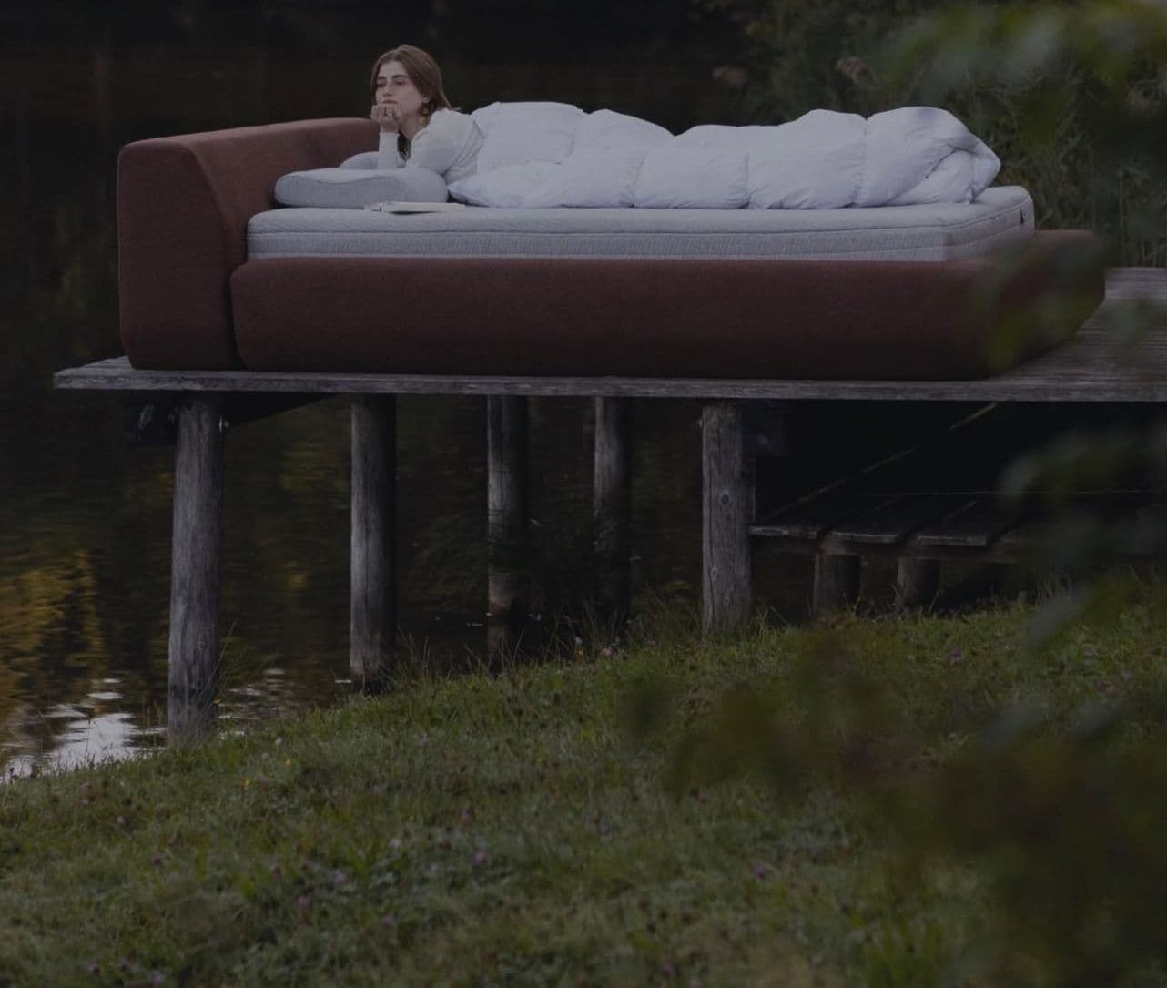 Frau entspannt auf einem Bett von Seven Sundays am Seeufer.